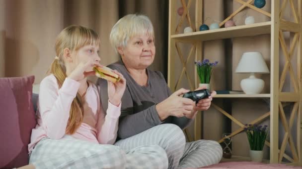Ξεκουραστείτε με ένα παιδί - μια ηλικιωμένη κυρία παίζει βιντεοπαιχνίδια με την εγγονή της — Αρχείο Βίντεο