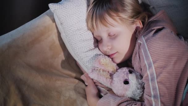 Ένα κορίτσι κοιμάται με το αγαπημένο της βελούδινο παιχνίδι. Άποψη από ψηλά — Αρχείο Βίντεο