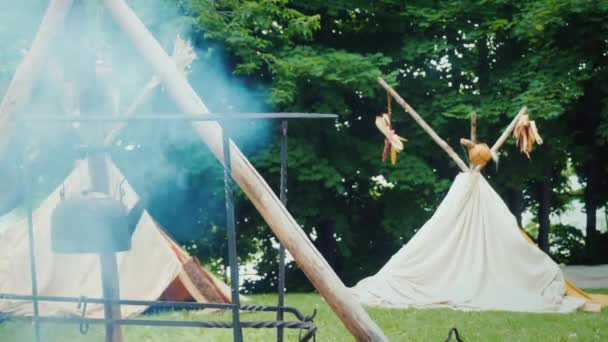 Indiaans kamp in het bos. Voedsel wordt op de voorgrond bereid, traditionele wigwam tenten zijn zichtbaar achter — Stockvideo