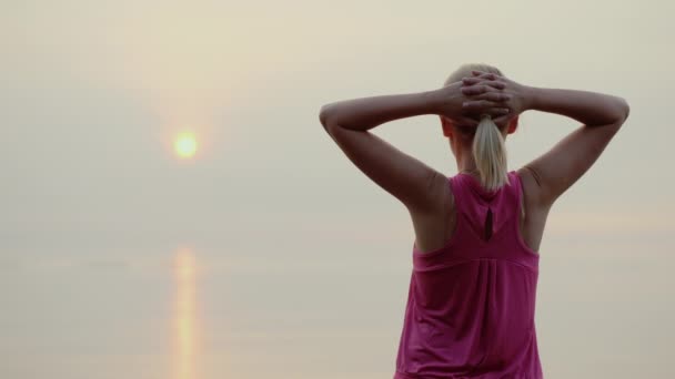 Vista trasera de la mujer fitness Confident mirando al amanecer sobre el mar — Vídeos de Stock