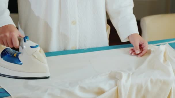 Mani femminili con una stiratura di ferro a una camicia elegante bianca — Video Stock