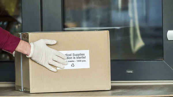 Courier brings a box with protective medical masks to the doorstep