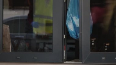 Gönüllü, insanların kendi kendilerini izole ettikleri evin kapısından bir çöp torbası alıyor.