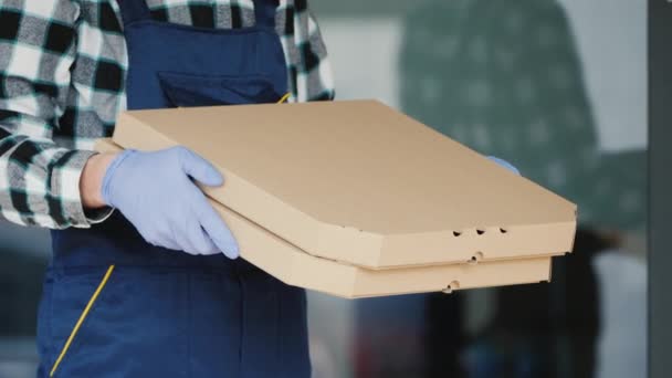 Säker leverans av pizzan, kuriren håller lådan i skyddshandskar. — Stockvideo