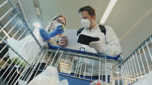 Молодая пара покупает фрукты в супермаркете во время эпидемии коронавируса — стоковое видео