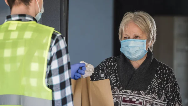 Eployee çalışanı yaşlı kadınlara yemek torbaları getiriyor.