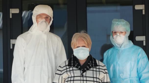 Portrait of an elderly woman with medics in protective suits. Fighting coronavirus — Stock Video