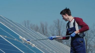 Adam ev elektrik santralinde güneş panellerini yıkıyor.