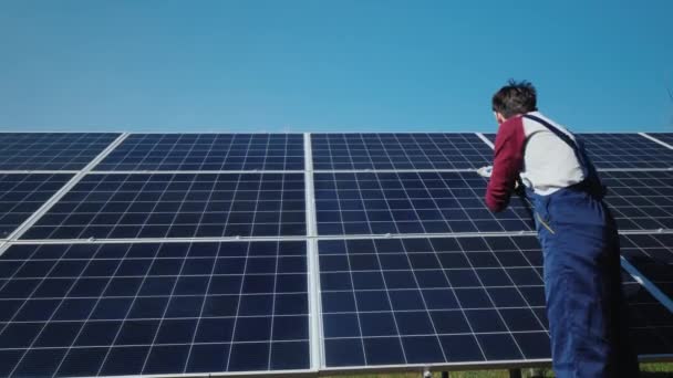 Visão traseira do homem lava painéis solares na usina de energia doméstica — Vídeo de Stock