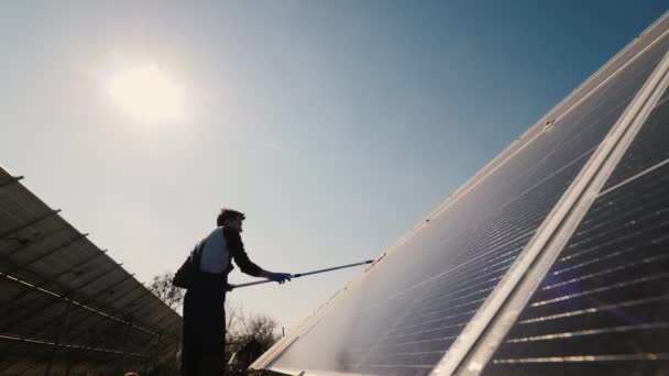 Silhueta de um homem que limpa poeira em painéis solares — Vídeo de Stock