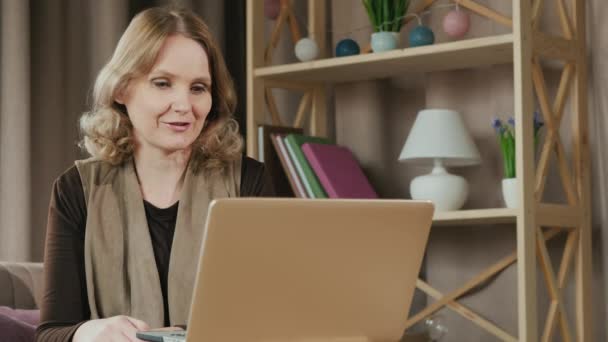 Egy középkorú nő videokapcsolaton keresztül kommunikál a rokonaival. Otthon, karanténban. — Stock videók