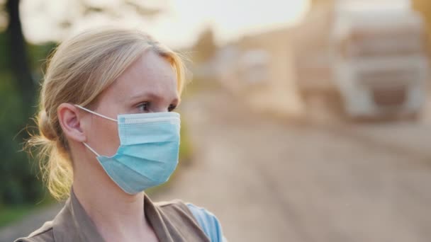 Портрет женщины в защитной маске на пыльной дороге. Концепция экологических проблем — стоковое видео