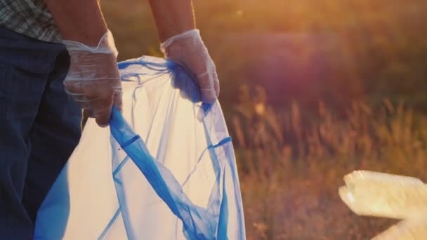 Vrijwilligers doen afval in plastic zakken. Reiniging van het park en zorg voor het milieu — Stockvideo