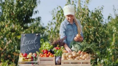 Küçük bir çiftçi çiftçi tezgahına sebze koyar.