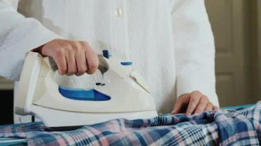 Kadınların elleri ekose gömleği ütülüyor