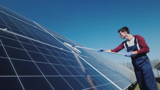 Вид збоку Чоловік миє сонячні панелі на домашній електростанції — стокове відео