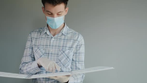 A monicoin in a protective mask looks at the catalog with samples of products. Working in quarantine — Stock Video