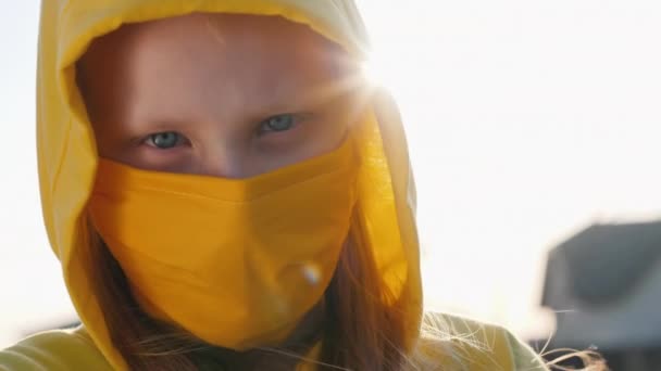 Портрет девушки в жёлтом капюшоне и жёлтой защитной маске — стоковое видео