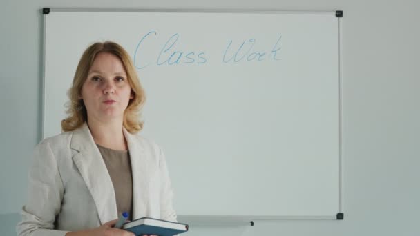 Professor leva lição na placa, olha para a câmera — Vídeo de Stock