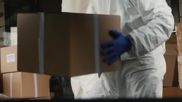 Чоловіки рухаються в захисних костюмах завантажують картонні коробки з ліками в автомобіль — стокове відео