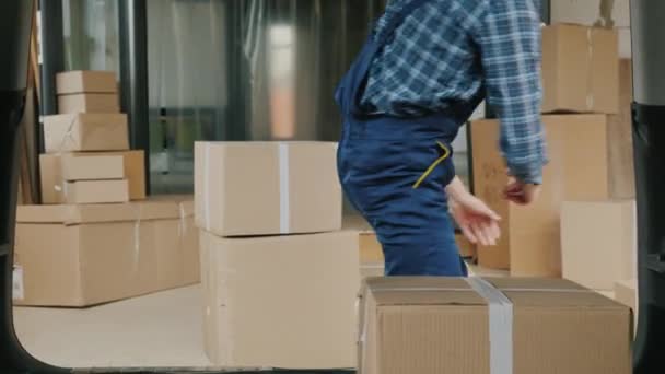 Wholesale warehouse worker loads cardboard boxes into the trunk of a van — Stock Video