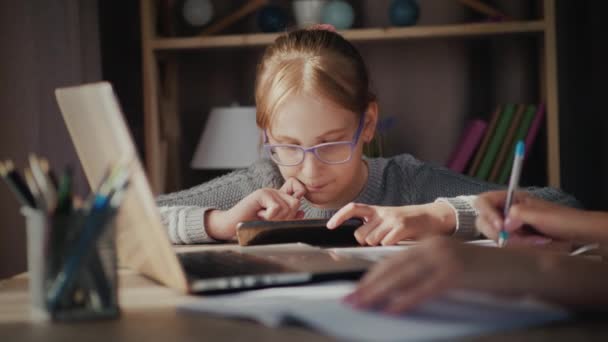 Ett barn leker på en smartphone nära en förälder som arbetar hemma i karantän — Stockvideo