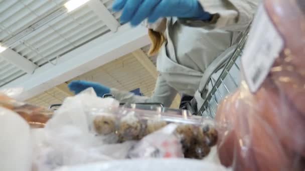 Het echtpaar laadt aankopen uit een trolley in de supermarkt. Draagt een beschermend masker en handschoenen — Stockvideo