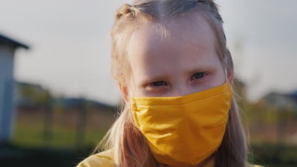 Retrato de una niña con una máscara protectora amarilla — Vídeo de stock