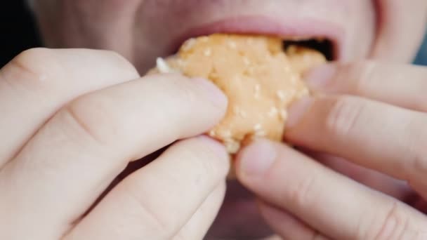 Un homme affamé mange avec impatience un hamburger, seule sa bouche est visible dans le cadre — Video