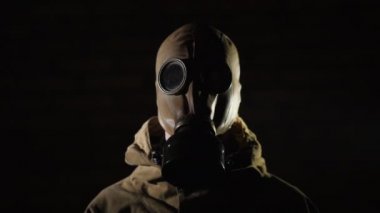 Siyah arka planda koruyucu giysili ve gaz maskeli bir adam.