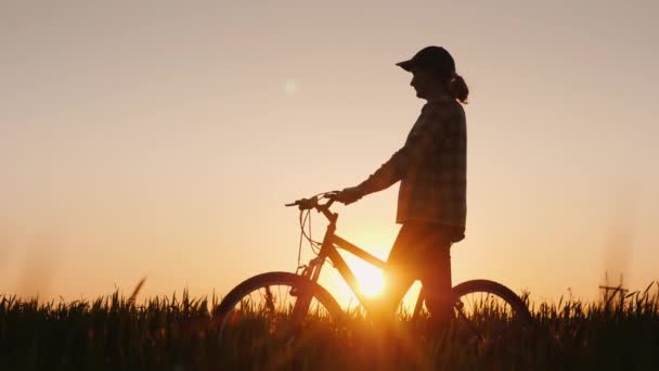 Mujer con bicicleta admira puesta de sol — Vídeos de Stock