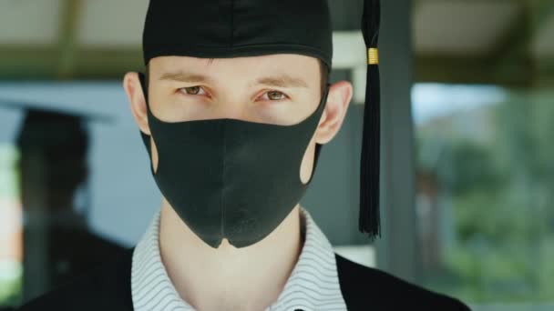 Портрет выпускника в шляпе-халате с защитной маской на лице — стоковое видео