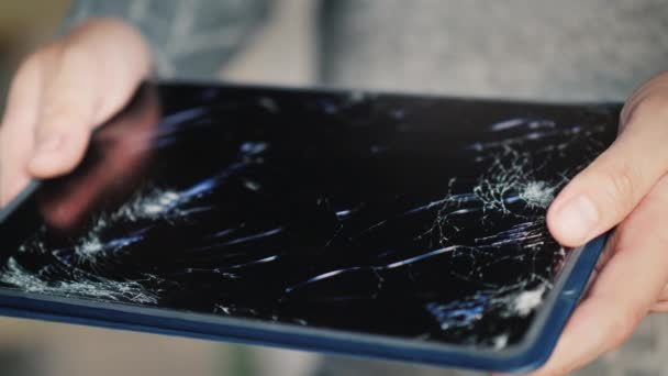 Un homme tient une tablette avec un écran cassé — Video