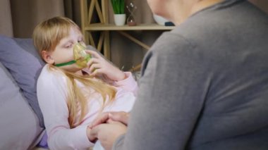 Soğuk bir çocuk özel bir maske takıyor, büyükannesinin yanında oturuyor.