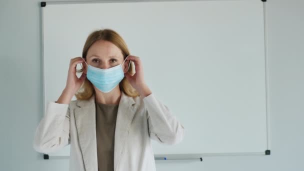 Female teacher wears protective mask in front of classroom — Stock Video