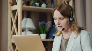 Kadın evden gelen müşterilerle iletişim kuruyor, kulaklıkla konuşuyor. Merkez Ofis