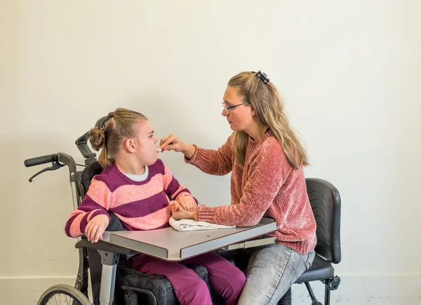 Un enfant handicapé en fauteuil roulant avec un travailleur bénévole — Photo