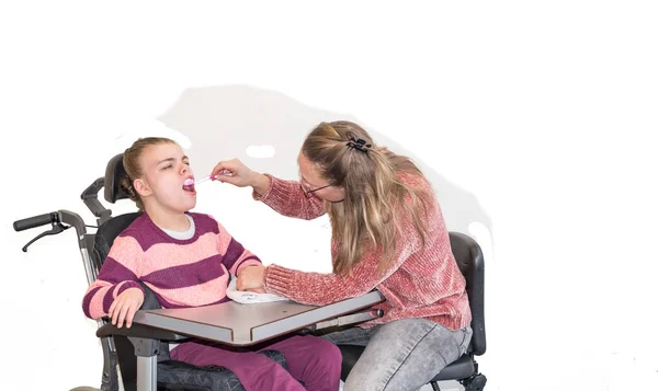 Ребенок-инвалид в инвалидном кресле вместе с добровольным работником — стоковое фото