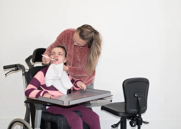 Niepełnosprawne dziecko w wózku inwalidzkim wraz z pracownikiem opieki dobrowolne — Zdjęcie stockowe