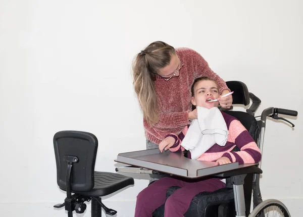 Engelli bir çocuğun bir gönüllü bakım işçi ile birlikte tekerlekli sandalyede — Stok fotoğraf