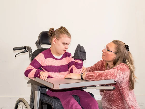 Un enfant handicapé en fauteuil roulant avec un travailleur bénévole — Photo