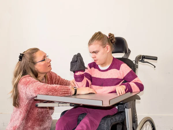 Ein behindertes Kind im Rollstuhl zusammen mit einer freiwilligen Betreuerin — Stockfoto