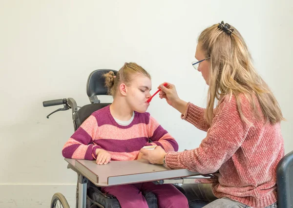 Un enfant handicapé en fauteuil roulant avec un travailleur bénévole — Photo