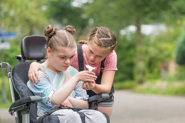 Özürlü Engelli bir çocuğun kız kardeşi ile rahatlatıcı dışında tekerlekli sandalyede — Stok fotoğraf
