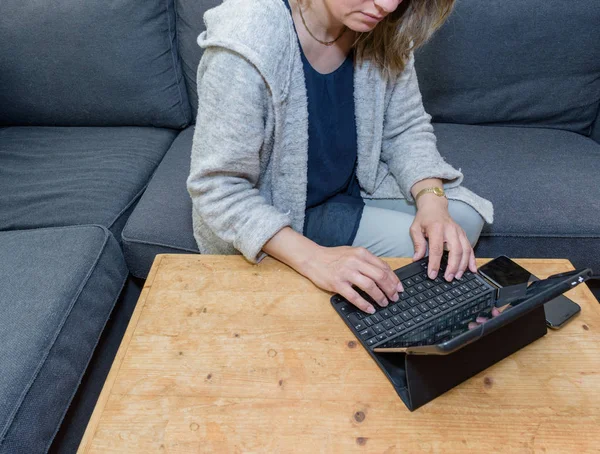 Una mujer que se relaja en casa usando una computadora portátil — Foto de Stock