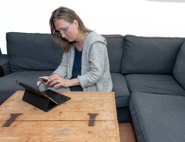Una mujer de mediana edad en casa usando su computadora portátil — Foto de Stock