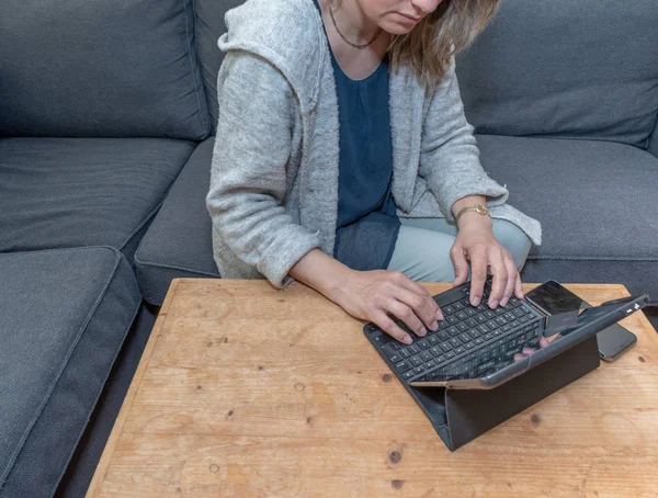 Una mujer de mediana edad en casa usando su computadora portátil — Foto de Stock