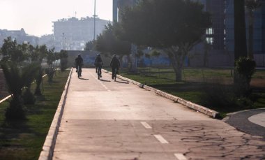 gün batımında şehirde yolda üç bisikletçi