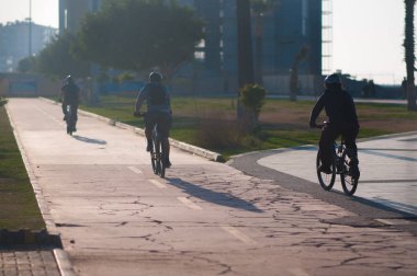 gün batımında şehirde yolda üç bisikletçi