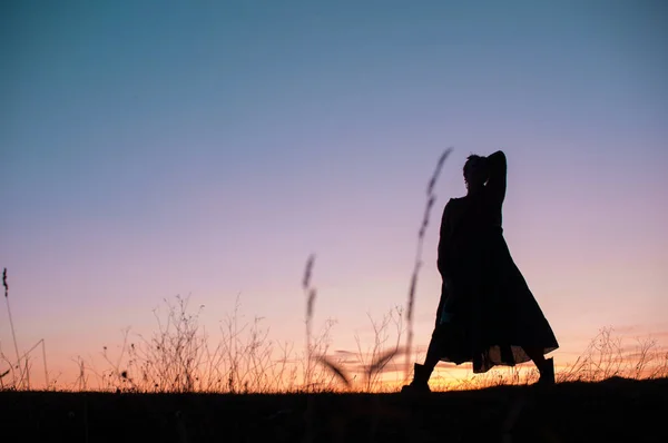 Silueta de una chica bailando sobre el fondo de una hermosa puesta de sol — Foto de Stock